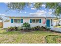 Charming single-story home with vibrant blue shutters and door, complemented by a manicured front yard at 1529 Essex N Dr, St Petersburg, FL 33710