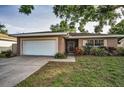 Charming single-story home featuring an attached garage, well-maintained lawn, and beautiful landscaping at 2010 Groveland Rd, Palm Harbor, FL 34683