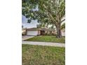Inviting single-story home with a large tree, a well-kept lawn, and an attached garage at 2010 Groveland Rd, Palm Harbor, FL 34683