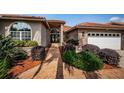 Close up of home's entry with brick walkway, an arched doorway, and lush landscaping at 2691 Saddlewood Ln, Palm Harbor, FL 34685