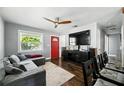 Cozy living room featuring a modern ceiling fan, red front door, and comfortable seating arrangement at 6212 S Adelia Ave, Tampa, FL 33616
