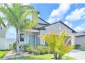 Charming home featuring a welcoming blue front door and lush tropical landscaping at 797 Olive Conch St, Ruskin, FL 33570