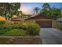 Charming single-story home at sunset featuring a two-car garage and lush landscaping for added curb appeal at 8405 Woodbridge Blvd, Tampa, FL 33615