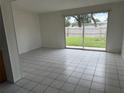 Spacious living room with white tile flooring and sliding glass doors to the backyard at 8801 Orange Blossom Dr, Seminole, FL 33772