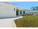 Side view of a home with a two-car garage, manicured lawn and inviting front entrance at 9073 Fruitland Ave, Englewood, FL 34224