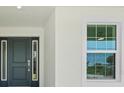 Close-up of the home's entrance featuring a front door with sidelights and white trim at 9073 Fruitland Ave, Englewood, FL 34224