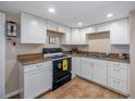 Functional kitchen featuring white cabinetry, black appliances, and tiled flooring, ready for your culinary creations at 11704 Orange Grove Ter, Riverview, FL 33569