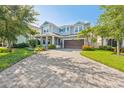 Charming two-story home boasts a paver driveway, manicured lawn, and vibrant landscaping at 12121 Rustic River Way, Tampa, FL 33635