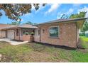 View of the front right side of the house with the yard, exterior brick and an entrance with a small porch at 1363 Cottage Grove Rd, Tarpon Springs, FL 34689