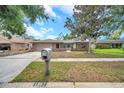 Charming single-story brick home featuring a spacious driveway and a mailbox on a well manicured lawn at 1363 Cottage Grove Rd, Tarpon Springs, FL 34689
