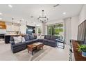Open-concept living room with a modern chandelier, stylish decor, and sliding glass doors to the backyard at 18144 Frame Bnd, Land O Lakes, FL 34638