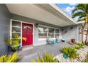 Cozy covered front porch with seating, potted plants, and a decorative red door at 3173 Fountainhead Dr, Largo, FL 33770