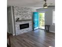 Living room showcasing modern fireplace, ceiling fan, tile accent wall, and a blue front door at 4470 Mainlands W Blvd, Pinellas Park, FL 33782