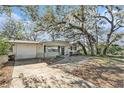 Inviting single-story home featuring mature trees and a well-maintained front yard and attached garage at 4928 Petunia Ct, New Port Richey, FL 34652