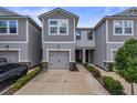 Gray townhome featuring a gray garage door, well-maintained landscaping, and a concrete driveway at 5813 Grand Sonata Ave, Lutz, FL 33558