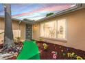 Inviting front entrance with a secure door, lush landscaping, decorative flowers, and a green walkway at 7631 Ironbark Dr, Port Richey, FL 34668