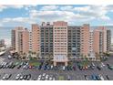 Front of tan condo building with beach view; wide parking lot in front at 880 Mandalay Ave # C513, Clearwater Beach, FL 33767
