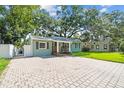 Charming single-story home showcasing manicured lawn and large brick paver driveway at 1208 E Crenshaw St, Tampa, FL 33604