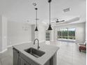 Bright open concept kitchen and dining area features neutral finishes, island seating, and sliding glass doors at 13524 Circa Crossing Dr, Lithia, FL 33547