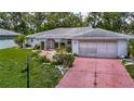 Single-Gathering home featuring a red brick driveway, mature landscaping, and an attached garage, providing comfortable living at 1607 New Bedford Dr, Sun City Center, FL 33573