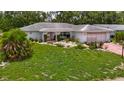 Charming home boasting a manicured lawn, beautiful landscaping, and a red brick driveway leading to an attached garage at 1607 New Bedford Dr, Sun City Center, FL 33573