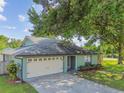 Single-story home featuring a two-car garage, light green exterior, and well-maintained landscaping at 17701 Sunrise Dr, Lutz, FL 33549