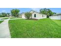 The house features an expansive green lawn, garden beds, and a mature tree at 247 Winthrop Dr, Spring Hill, FL 34609