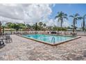 Outdoor pool area with brick-paved deck, lounge chairs, tables, and lush landscaping at 2901 W 26Th St # 301, Bradenton, FL 34205