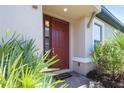 Welcoming entryway with a red front door, sidelight window, and lush landscaping at 3312 Francoa Dr, Odessa, FL 33556