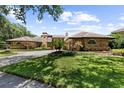 Charming brick home displays lush landscaping, a three-car garage, a curved driveway, and mature landscaping at 3772 Woodridge Pl, Palm Harbor, FL 34684