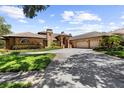 Beautiful brick home boasts a three-car garage, curved driveway, mature trees, and manicured landscaping at 3772 Woodridge Pl, Palm Harbor, FL 34684