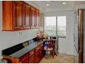 Wet bar with granite counters and cherry cabinets, next to stainless steel refrigerator and window at 650 Island Way # 606, Clearwater Beach, FL 33767