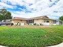 Sprawling home exterior featuring a well-maintained lawn and mature trees against a blue sky at 8110 Damara Dr, New Port Richey, FL 34653