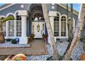 Inviting front entrance featuring decorative pots, white columns, brick pavers and lush landscaping at 9220 Hidden Water Cir, Riverview, FL 33578