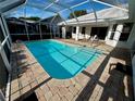 A refreshing screened-in pool with a brick paved patio and a sunny seating area at 1039 Greenturf Rd, Spring Hill, FL 34608