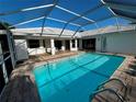 A refreshing screened-in pool with a brick paved patio and a sunny seating area at 1039 Greenturf Rd, Spring Hill, FL 34608