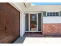 Close-up of front entrance featuring a stained wood front door with decorative glass and brick accents at 13883 Jamaica Dr, Seminole, FL 33776