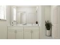 Well-lit bathroom featuring double vanity with marble countertop, neutral cabinets, and modern fixtures at 1554 Serenity Outlook Ct, Lutz, FL 33548