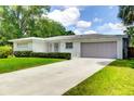 Well-kept one-story home with lush lawn, a long driveway, and attached garage at 2205 N Riverside Dr, Tampa, FL 33602
