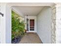 Inviting entryway featuring a covered porch with textured walls, stone accents, and a charming front door at 2418 Cardwell Way, Sarasota, FL 34231