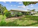 This single-story home's exterior features lush green landscaping, a gray shingle roof, and stone accents at 2418 Cardwell Way, Sarasota, FL 34231