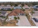 An aerial view of a beautiful home with a paved driveway and a cozy front porch in a quiet neighborhood at 2457 E Del Webb Blvd, Sun City Center, FL 33573