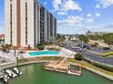 Exterior shot of a waterfront condo building with a pool, tiki umbrellas, and parking at 255 Dolphin Pt # 207, Clearwater Beach, FL 33767