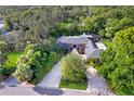 Stunning brick home with lush landscaping, a circular driveway, and a screened pool area at 302 Eastleigh Dr, Belleair, FL 33756