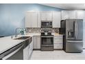 Bright kitchen with stainless steel appliances, farmhouse sink, gray cabinets, and a decorative backsplash at 3029 Brookfield Ln, Clearwater, FL 33761