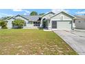 Inviting single-story home featuring a two-car garage, decorative front door, and lush green lawn at 4399 Dior Rd, Spring Hill, FL 34609