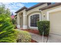 Close up of home exterior with arched window, columns, green shrubbery, and front yard at 8836 Alafia Cove Dr, Riverview, FL 33569