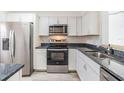 Well-lit kitchen featuring stainless steel appliances, black countertops, and white cabinetry at 900 Cove Cay Dr # 1B, Clearwater, FL 33760