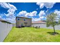 Large backyard with a white fence, green lawn, landscaping, and seating area at 10360 Blue Plume Ct, Riverview, FL 33578