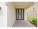 Home entryway featuring a dark front door with glass panels, complemented by stone pavers and exterior walls at 13299 Wildgrass Trl, Odessa, FL 33556